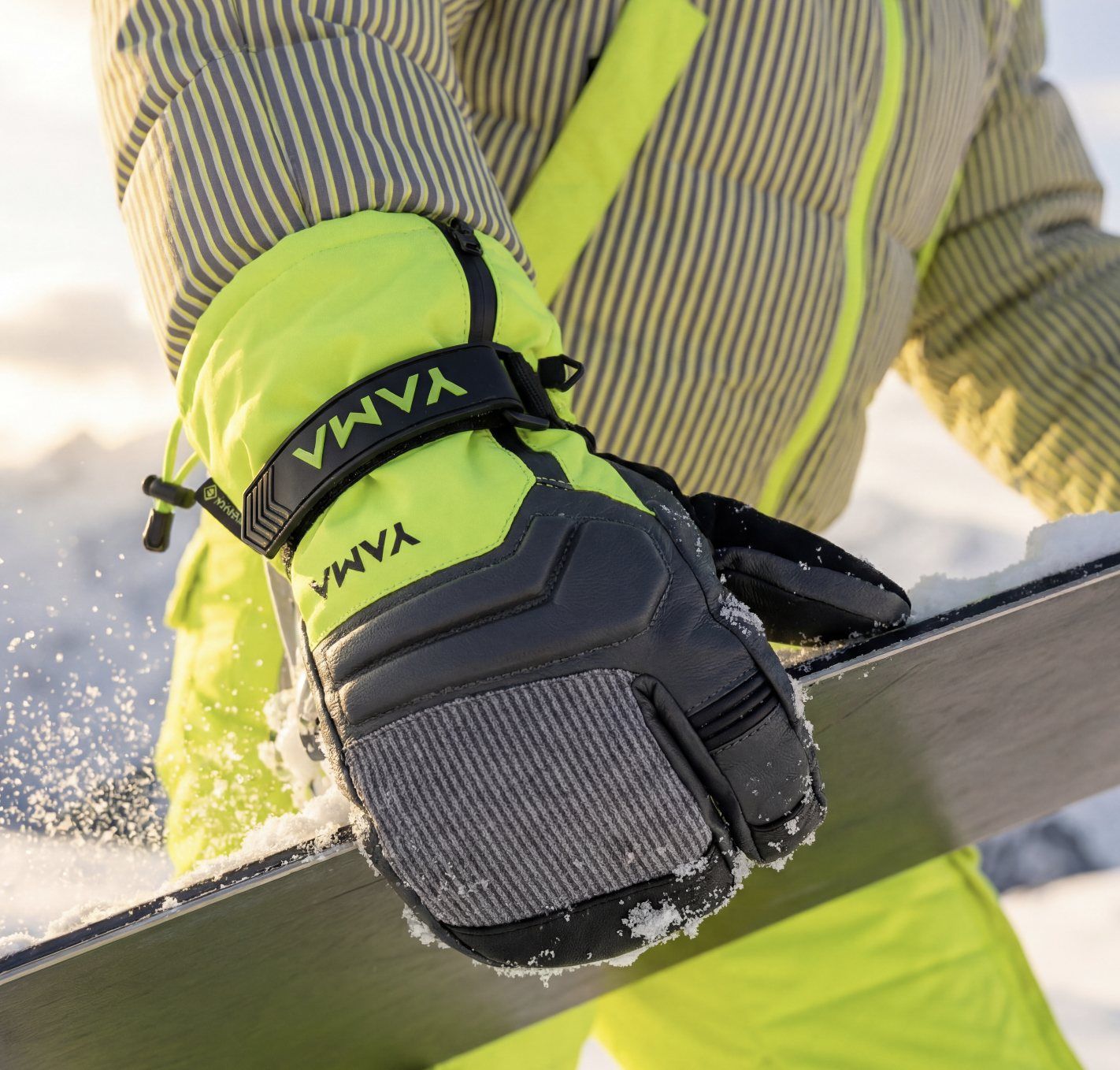 Moufle de snowboard YAMA jaune fluo et grise tenant une planche dans la neige